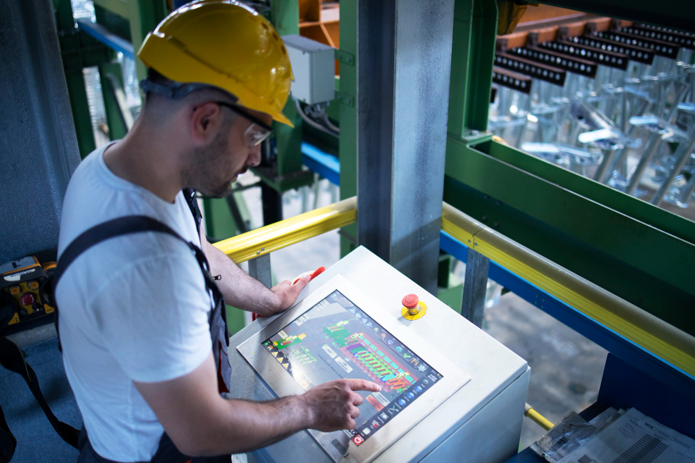 Industrial technician operating a digital control panel inside a manufacturing facility.